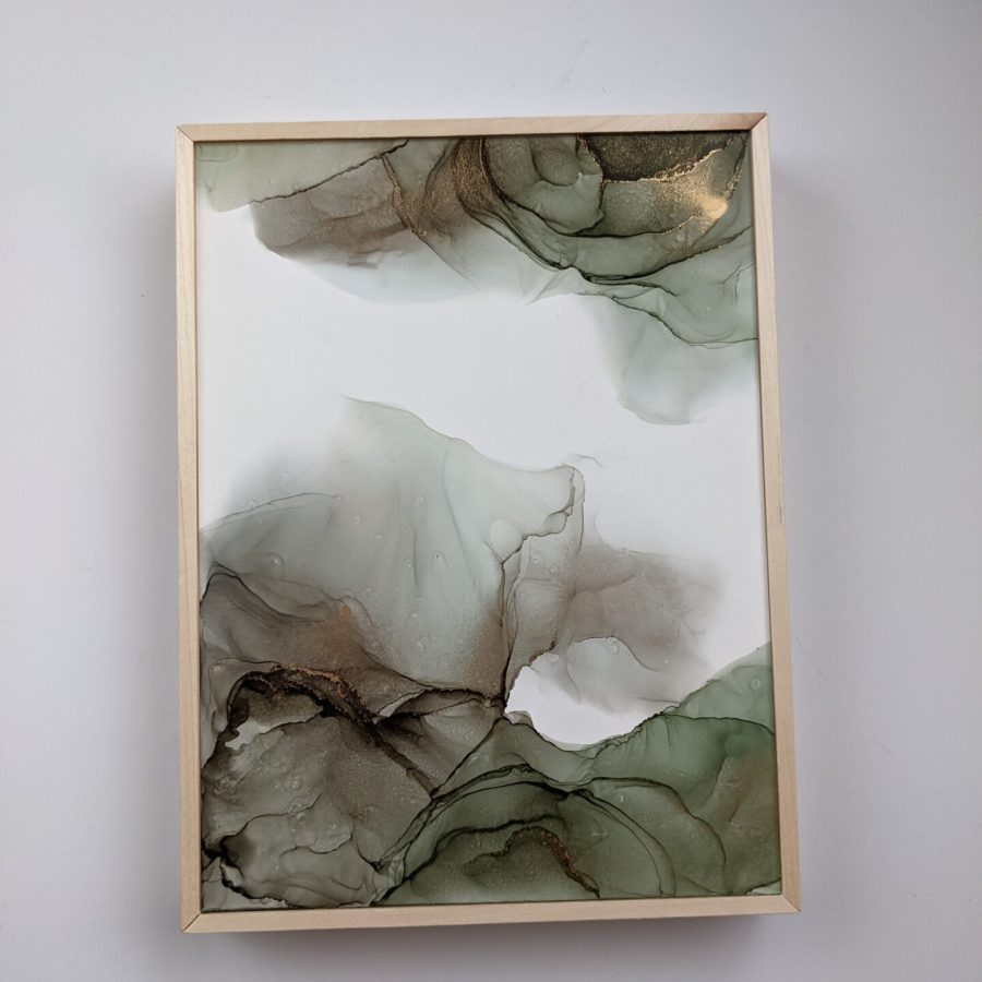 A soft green abstract art piece sits in a birch frame on a white background.  The piece is full of soft greens and gold lines cut through the darkest areas.  The piece resembles a wave, reaching clockwise around the composition, only to fade from the top right without meeting the bottom half.