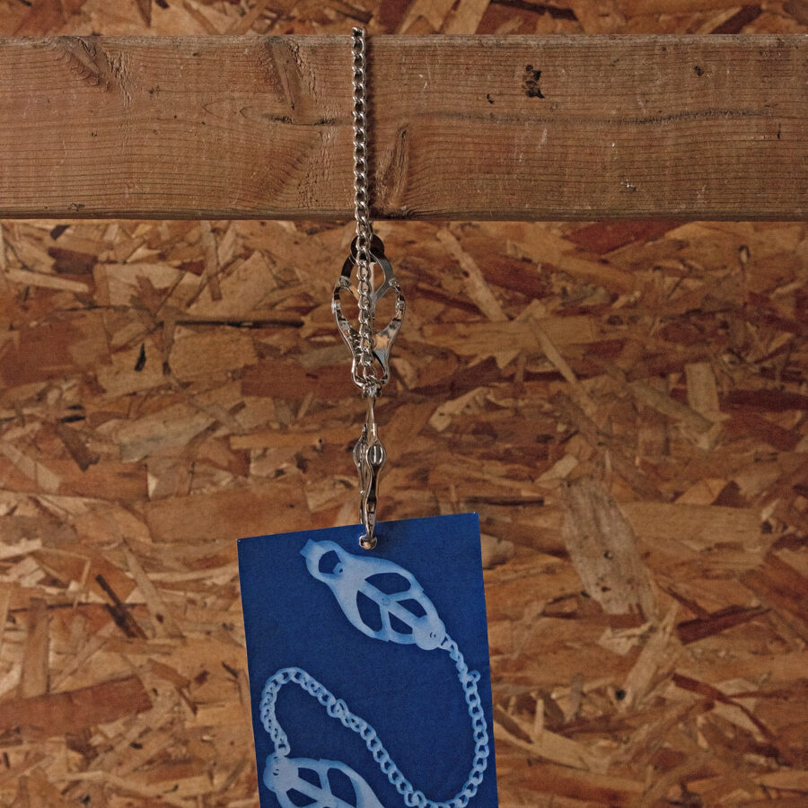 blue cyanotype print suspended by silver clamps