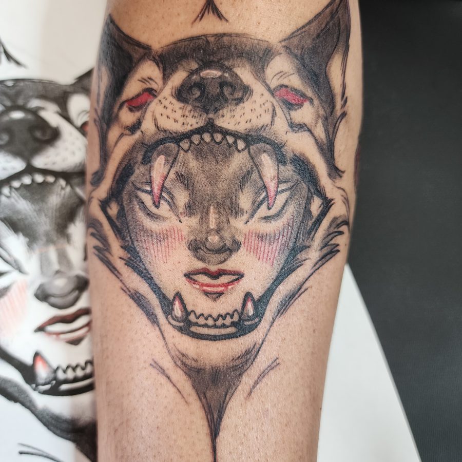Tattoo of a woman's face inside of a wolf's mouth head