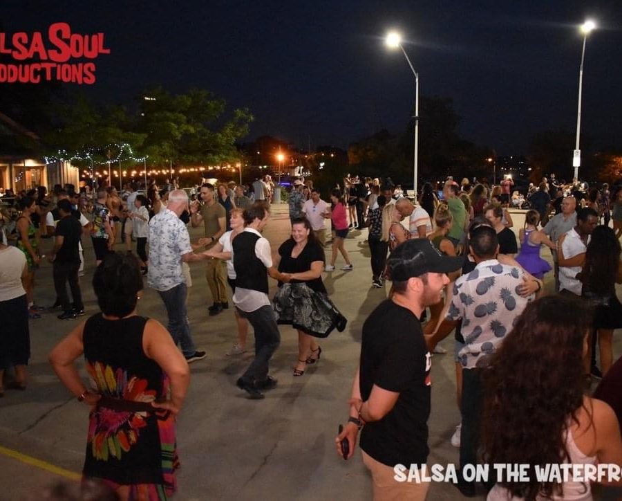 A large crowd dancing salsa in the evening on the skating rink at Pier 8. 