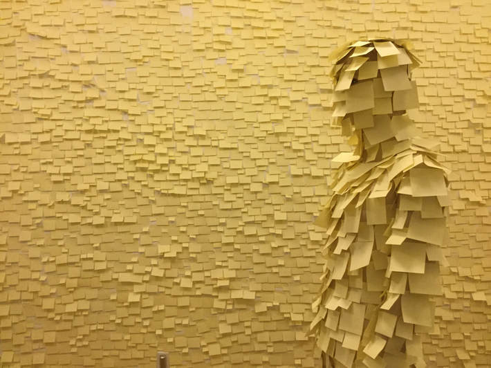 Grudge, 2018, The Assembly Gallery, A figure covered in yellow post its infront of a wall covered in yellow post its.