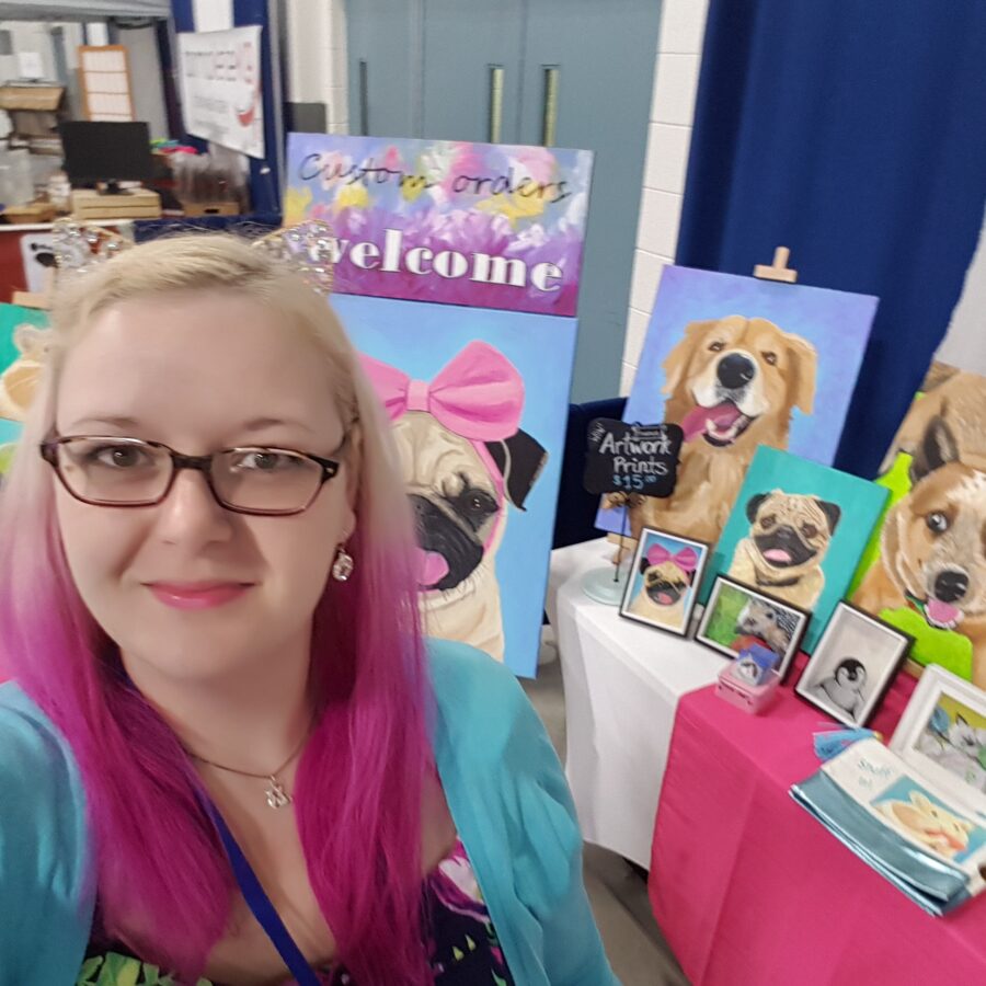 A woman with pink hair standing in front of pet art.